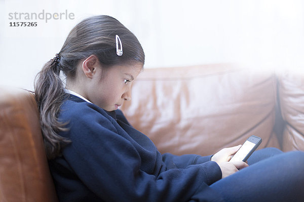 Mädchen spielt mit Smartphone auf dem Sofa