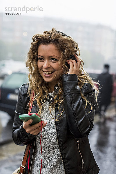 Frau auf der Straße hört Musik über Kopfhörer