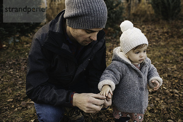 Vater hält Hand eines kleinen Mädchens im Wald