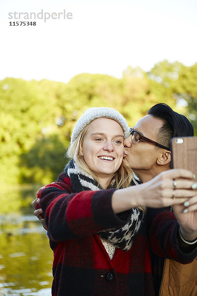 Ehepaar mit Smartphone am Seeufer des Parks