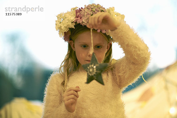 Mädchen mit Blumen im Haar hält und den Sternenschmuck betrachtet