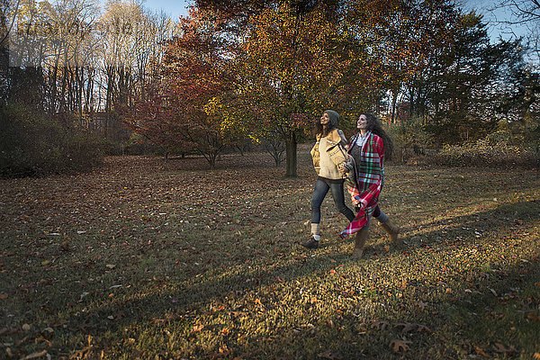 Zwei Freundinnen schreiten durch den Herbstpark