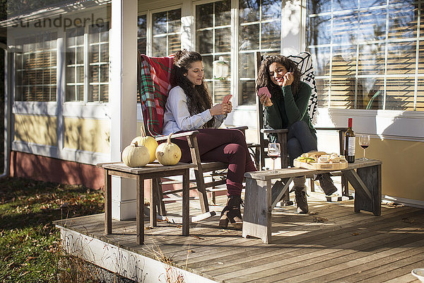 Zwei junge Freundinnen beim Kartenspiel auf der Terrasse