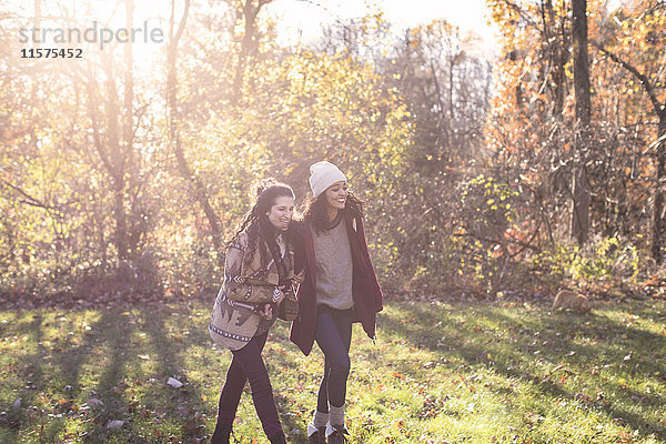 Zwei junge Freundinnen spazieren im Herbst auf dem Feld
