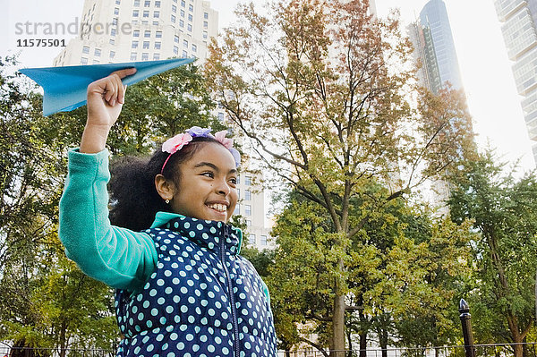 Mädchen wirft lächelnd Papierflugzeug  New York  USA