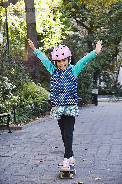 Mädchen auf Skateboard Arme lächelnd erhoben  New York  USA