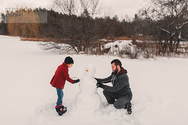Vater und Tochter beim Schneemannbauen
