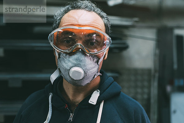 Porträt eines Metallarbeiters mit Staubmaske und Schutzbrille in der Schmiedewerkstatt