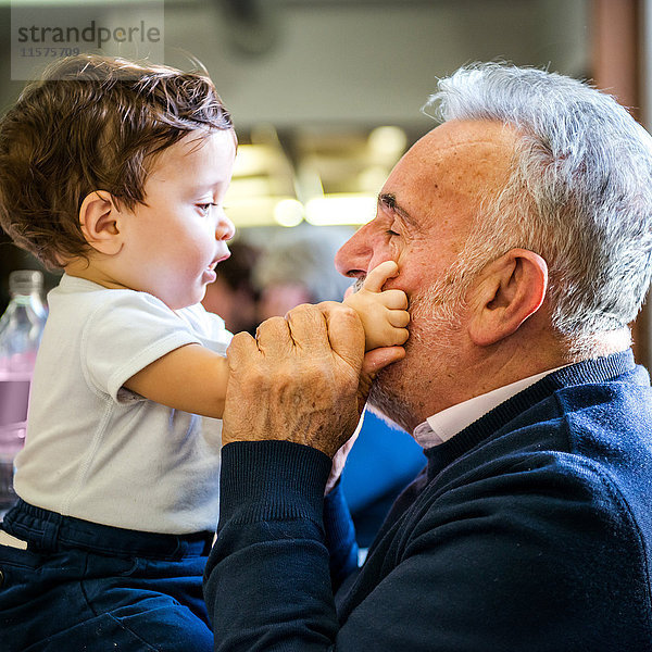 Älterer Mann trifft Baby-Enkel im Café von Angesicht zu Angesicht