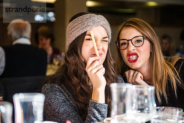 Porträt von zwei jungen Frauen  die im Café Gesichter ziehen