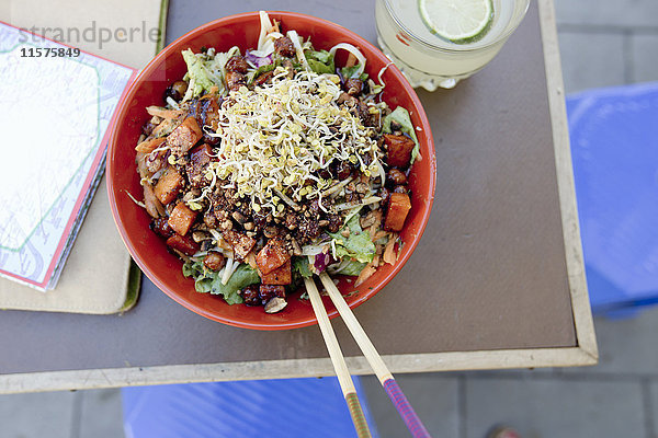 Draufsicht auf vegetarischen Salat mit Nudeln auf dem Tisch eines Straßencafés