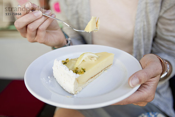 Mittelteil einer Frau  die ein Stück Kuchen im städtischen Straßencafé isst