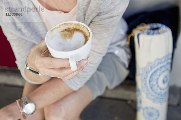 Mittelteil einer Frau mit leerer Kaffeetasse im städtischen Straßencafé