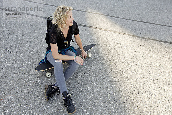 Auf dem Skateboard sitzende Skateboardfahrerin