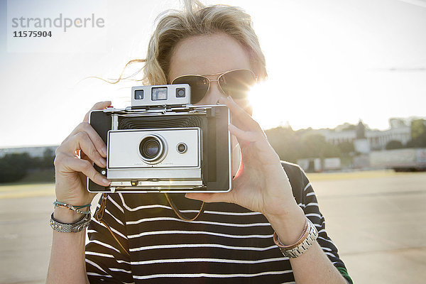 Mittlere erwachsene Frau  die mit einer Oldtimer-Kamera fotografiert