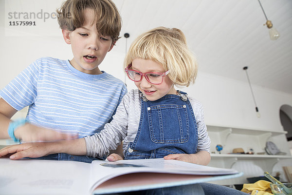 Mädchen spielt Streit mit dem Bruder über ein Märchenbuch in der Küche