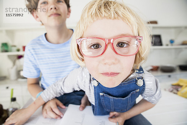 Bildnis eines süßen Mädchens mit Brille und Bruder in der Küche