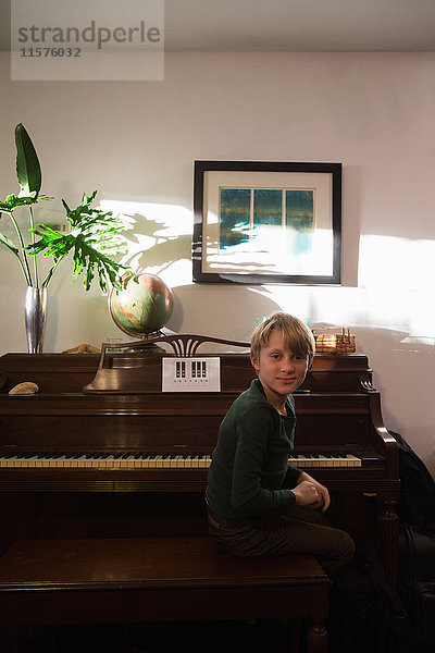 Porträt eines Jungen  der im Wohnzimmer am Klavier sitzt