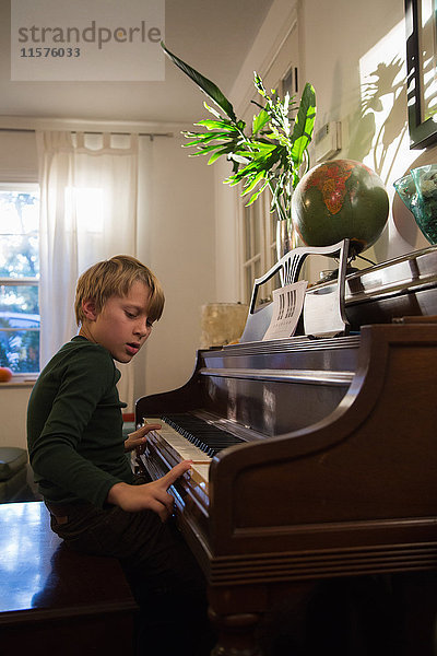 Junge spielt Klavier im Wohnzimmer