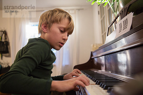 Junge spielt Klavier im Wohnzimmer