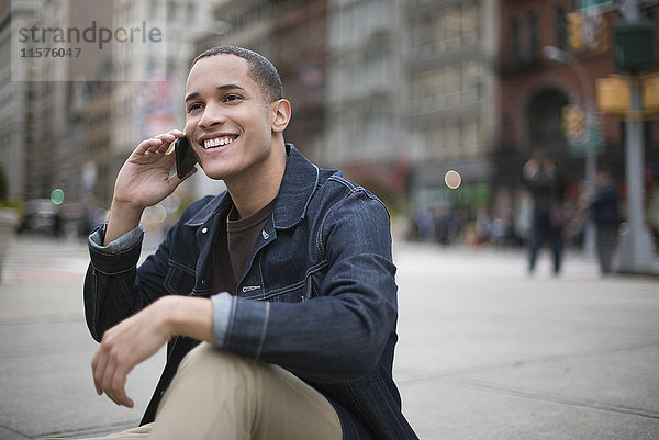 Junger Mann auf der Straße  der ein Smartphone benutzt  Manhattan  New York  USA