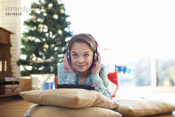 Mädchen liegt auf dem Wohnzimmerboden und hört zu Weihnachten Kopfhörer