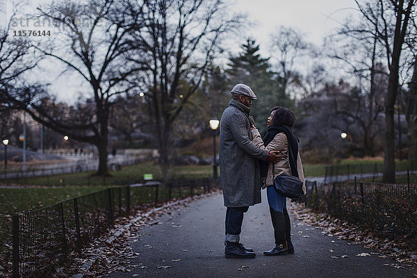 Romantisches Paar steht sich in der Abenddämmerung im Park gegenüber