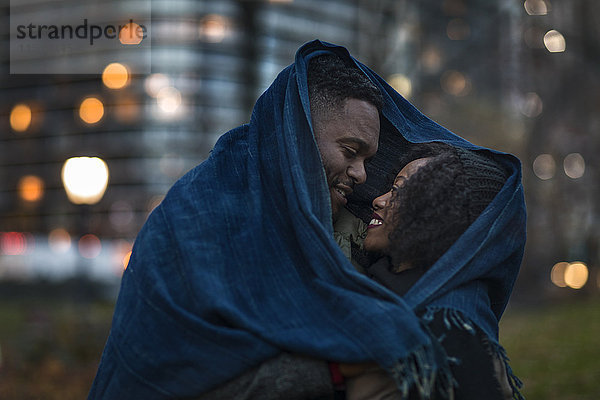 Romantisches Paar in eine Decke gehüllt in der nächtlichen Stadt