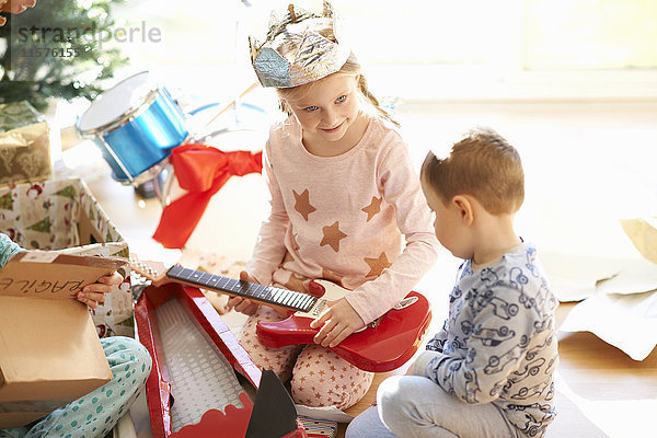 Mädchen und Bruder spielen am Weihnachtstag mit Spielzeuggitarre