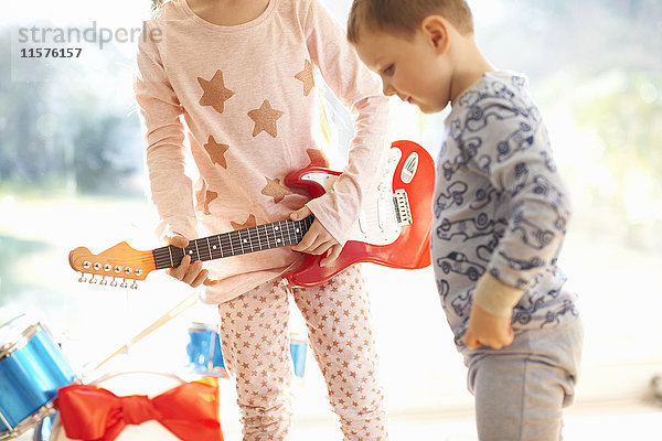 Mädchen und Bruder spielen am Weihnachtstag mit Spielzeuggitarre