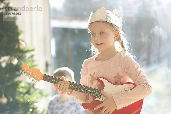 Mädchen spielt mit Spielzeuggitarre am Weihnachtstag