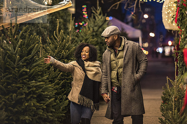 Ehepaar wählt Weihnachtsbaum auf dem nächtlichen Weihnachtsmarkt aus  New York  USA