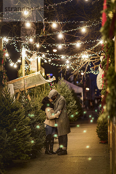 Romantisches Paar küsst sich nachts auf dem Weihnachtsmarkt  New York  USA