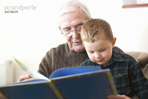 Älterer Mann liest Enkel Buch vor