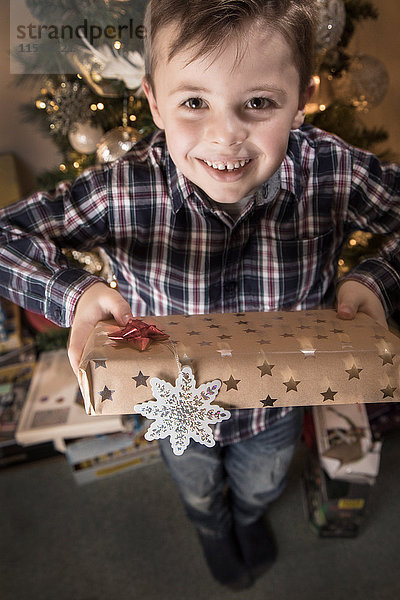Porträt eines Jungen  der ein Weihnachtsgeschenk überreicht