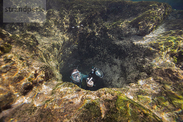 Mann in Unterwasserhöhle mit Kamera