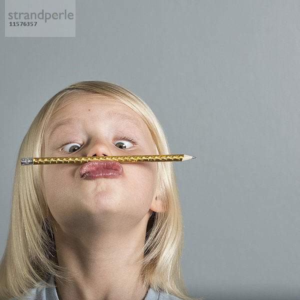 Porträt eines Jungen  der seinen Bleistift auf gerunzelten Lippen balanciert
