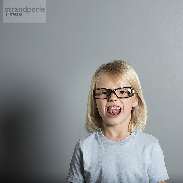 Porträt eines Jungen mit Brille und herausgestreckter Zunge