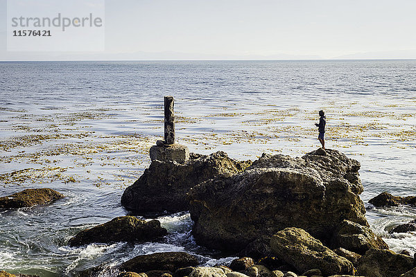 Älterer Mann  auf Felsen am Meer stehend  schaut auf Ansicht