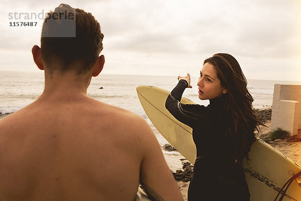 Zwei Freunde gehen auf das Meer zu  Surfbretter tragend  Rückansicht