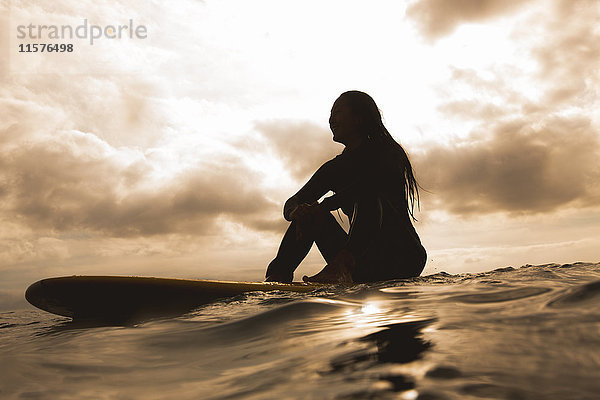 Junge Frau im Meer  auf einem Surfbrett sitzend