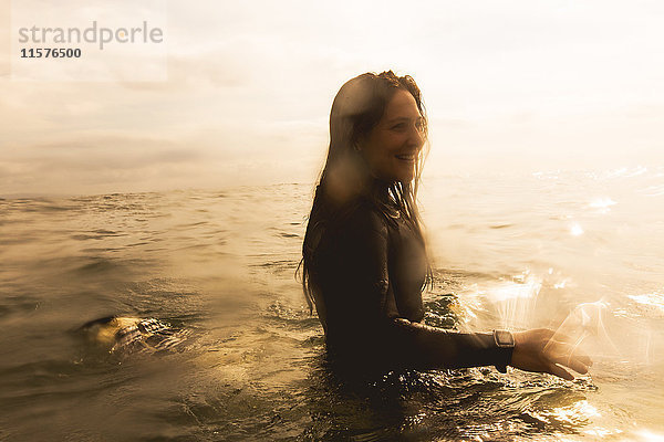 Junge Frau im Meer  auf einem Surfbrett sitzend