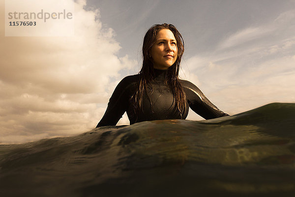 Junge Frau im Meer  auf einem Surfbrett sitzend  paddelnd
