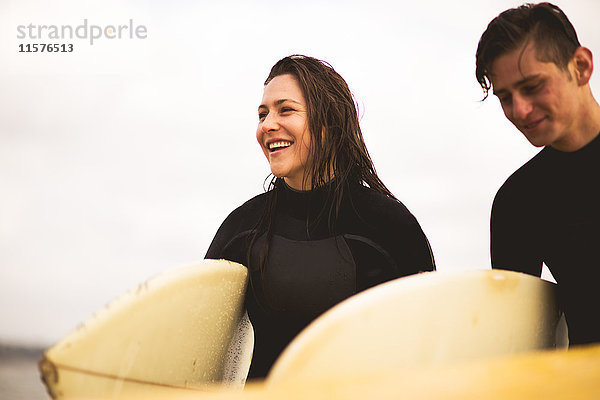 Freunde gehen vom Meer weg  tragen Surfbretter