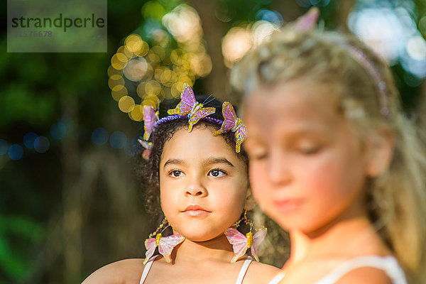 Zwei junge Mädchen  im Freien  mit Schmetterlingen im Haar