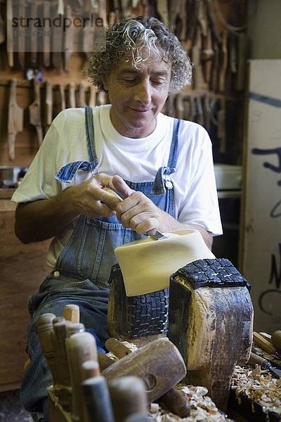 Schreiner mit Meißel auf Holzform für Kopfbedeckungen in der Werkstatt