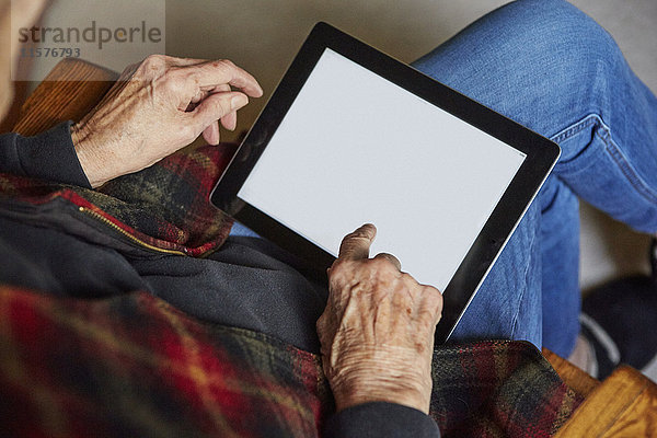 Ältere Frau auf Stuhl sitzend  mit digitalem Tablett  erhöhte Ansicht
