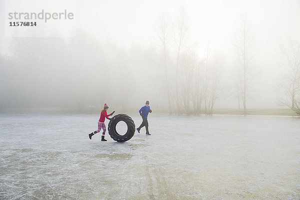 Frau rollt Reifen auf gefrorenem See