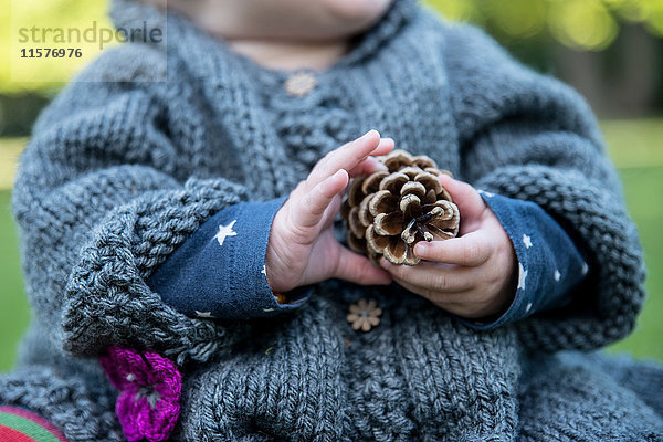 Mittelteil des Mädchens mit Pinienzapfen im Park