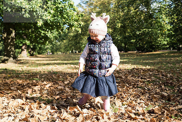 Weibliches Kleinkind im Herbstlaub im Park